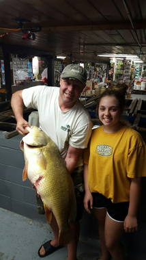 Amelia Whalen stands with her father who holds the record-breaking fish.